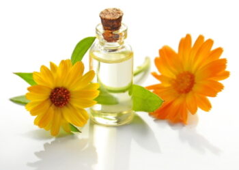 Fläschen mit Massageöl und gelber und orangener Ringelblumen